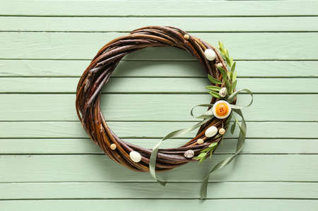 Beautiful Easter wreath with bow and branches on green wooden backgroundの写真素材