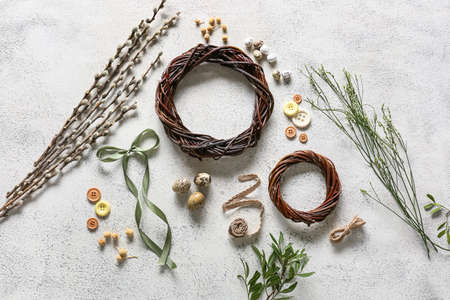 Composition with Easter wreaths, bow, pussy willow branches and buttons on light background
