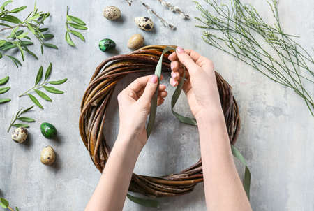 Woman making Easter wreath on gray backgroundの写真素材