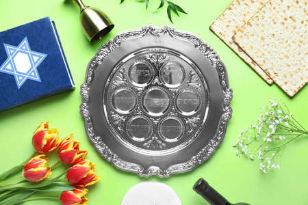 Composition with Passover Seder plate, matza, flowers and Torah on green background