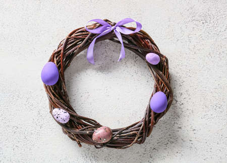 Beautiful wreath with Easter eggs on light backgroundの写真素材