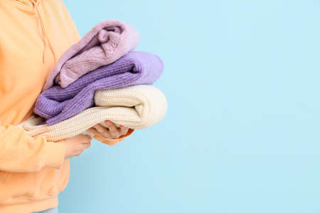 Woman with stack of knitted sweaters on blue backgroundの写真素材