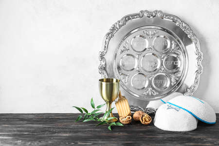 Passover Seder plate with kippah and cup on table against white background