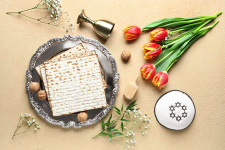Passover Seder plate with matza, tulip flowers, kippah and cup on color backgroundの写真素材