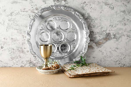 Passover Seder plate with cup of wine, walnuts and matza on table against grunge backgroundの写真素材