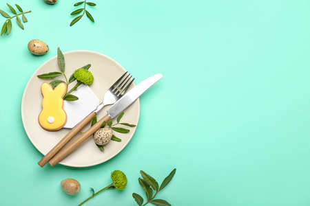 Stylish table setting with Easter cookie on turquoise background