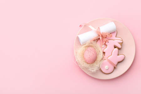 Stylish table setting with Easter cookies on pink background