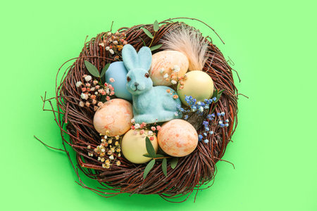 Nest with painted Easter eggs, bunny and flowers on green backgroundの写真素材