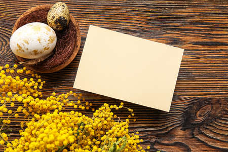 Beautiful Easter composition with blank card, eggs and flowers on wooden backgroundの写真素材