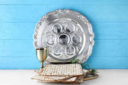 Passover Seder plate with cup of wine and matza on table against color wooden background