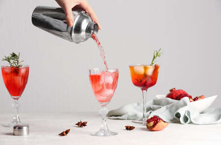 Woman pouring tasty pomegranate cocktail into glass