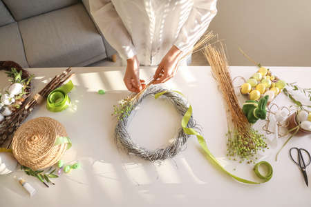 Woman making beautiful Easter wreath at table, closeupの写真素材