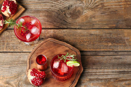 Glasses of tasty pomegranate cocktail and measure cup on wooden backgroundの写真素材