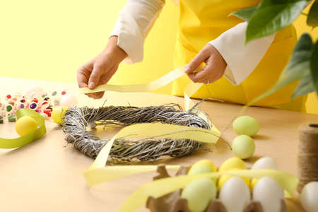 Woman making beautiful Easter wreath at table, closeupの写真素材