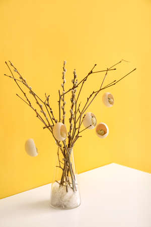 Creative composition with pussy willow branches and Easter eggs on table near color wallの写真素材