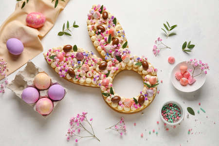 Composition with beautiful cake and painted eggs for Easter celebration on light backgroundの写真素材