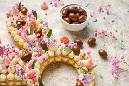 Beautiful cake and candies for Easter celebration on light background, closeup