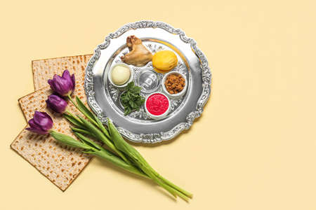 Passover Seder plate with traditional food and tulip flowers on light backgroundの写真素材