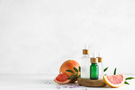 Composition with grapefruit essential oil and fruits on light backgroundの写真素材