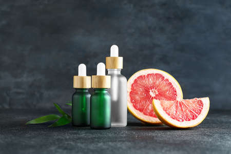 Bottles with essential oil and ripe grapefruit on dark backgroundの写真素材