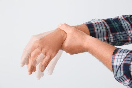 Hands of mature man with Parkinson syndrome on light backgroundの写真素材