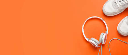 Sports shoes with headphones on orange background with space for textの写真素材