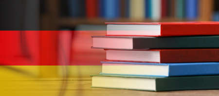 Collage with stack of books on table and flag of Germanyの写真素材