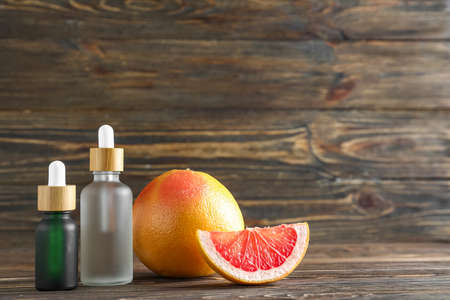 Bottles of essential oil and ripe grapefruit on wooden backgroundの写真素材