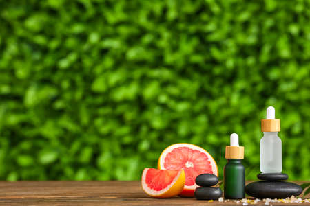 Composition with bottles of grapefruit essential oil and spa stones on table outdoorsの写真素材