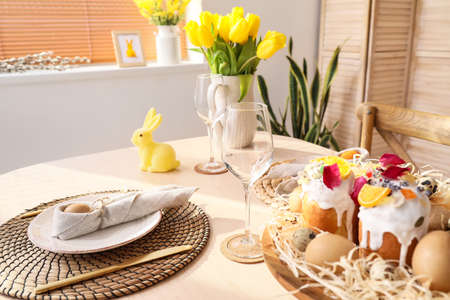 Stand with Easter cakes and eggs on served dining table