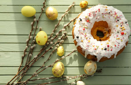 Tasty Easter cake with eggs and pussy willow branches on color wooden background