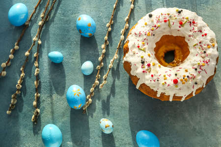 Tasty Easter cake with eggs and pussy willow branches on color background
