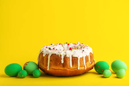 Tasty Easter cake and eggs on yellow background
