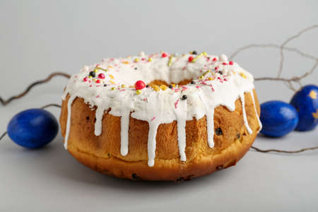 Tasty Easter cake and eggs on gray background