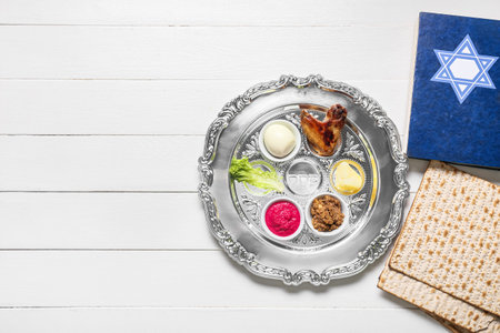 Passover Seder plate with traditional food, matza and Torah on white wooden background