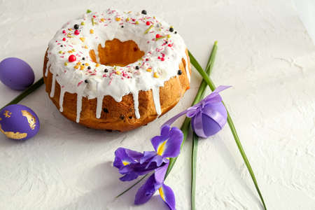 Tasty Easter cake with eggs and flowers on light background