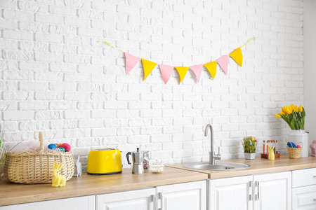 Kitchen counter with different utensils and Easter decor near white brick wallの写真素材
