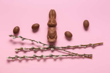 Chocolate Easter bunny, eggs and pussy willow on pink background