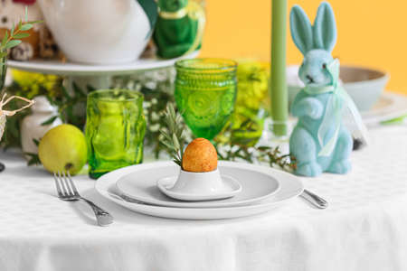 Holder with Easter egg and eucalyptus branch on served table