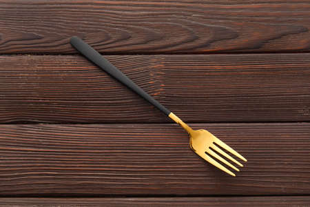 Stylish stainless steel fork on dark wooden backgroundの写真素材