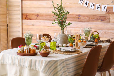 Stylish Easter table setting near wooden wall
