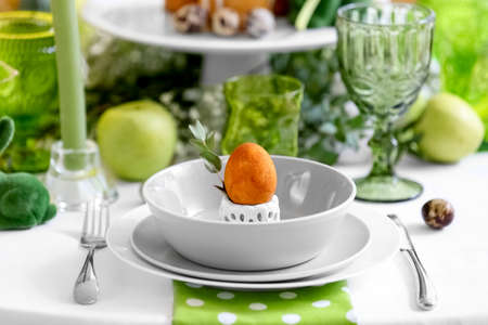 Dinnerware with Easter egg and eucalyptus branch on served table