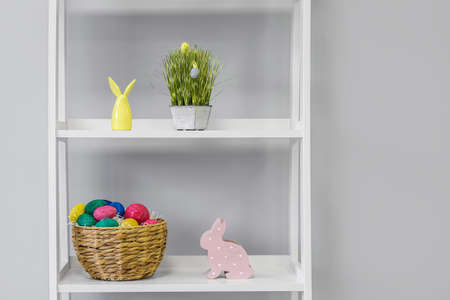 Shelf unit with Easter eggs and rabbits near light wall in children's roomの写真素材