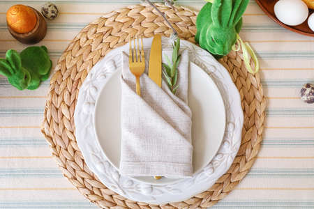 Plates and cutlery decorated with eucalyptus branch on table served for Easter celebration
