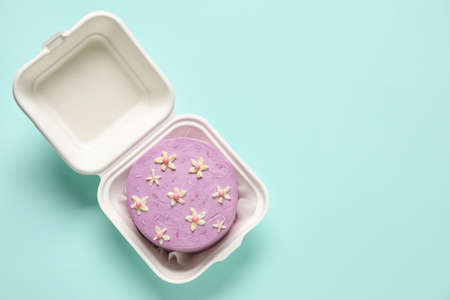 Plastic lunch box with tasty bento cake on turquoise backgroundの写真素材