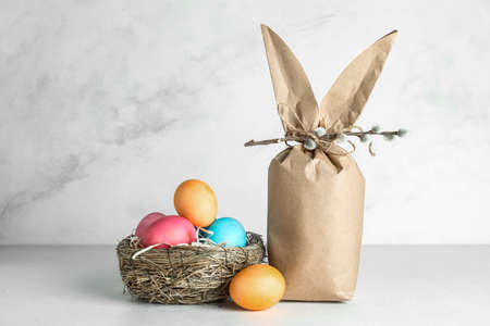 Easter bunny gift bag and nest with colorful eggs on light background