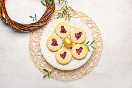 Plate with delicious Easter cookies on light background