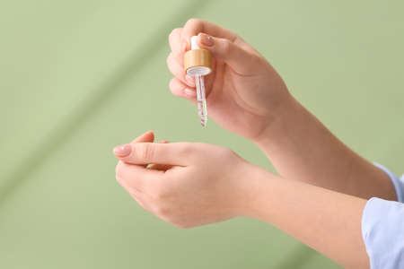 Woman applying serum onto hand against color background, closeupの写真素材
