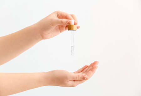 Woman applying serum onto hand on white background, closeupの写真素材