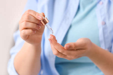 Woman applying serum onto hand, closeup